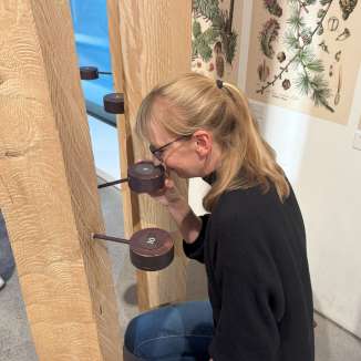 Eine blonde Frau riecht an Dosen, die verschiedene Dufte des Waldes beinhalten.