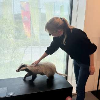 Eine blonde Frau streichelt einen ausgestopften Dachs.